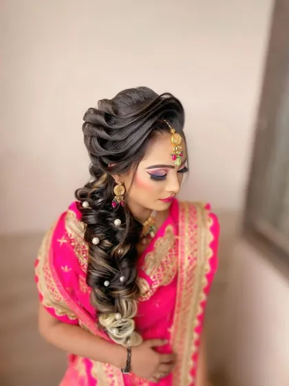 A closer look at the details of a pearl adorned party braid. The combination of twists and a voluminous braid creates a sophisticated hairstyle for any wedding event.