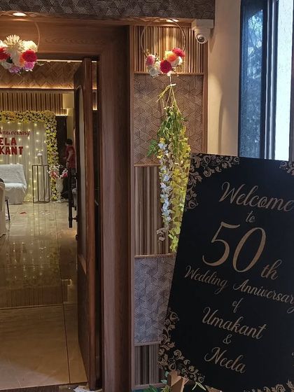 The view from the entrance of the 50th wedding anniversary party, showing the welcome sign and a glimpse of the main stage decoration.