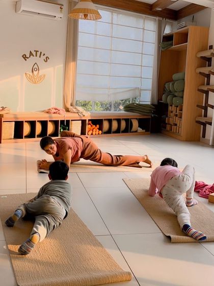 An instructor helps a young student with a lizard pose, providing gentle encouragement and support.