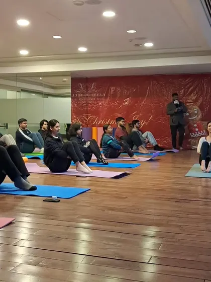Leading a corporate class through a seated warm-up. Even a short session can help improve focus and reduce stress during the workday.