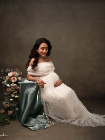 A moment of quiet reflection. This elegant pose in a white gown with floral details is full of peace and grace.