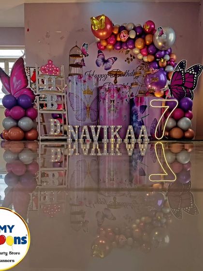 A butterfly-themed seventh birthday with a reflective floor. The purple and silver decor, neon '7', and butterfly cutouts create a modern and stylish look.