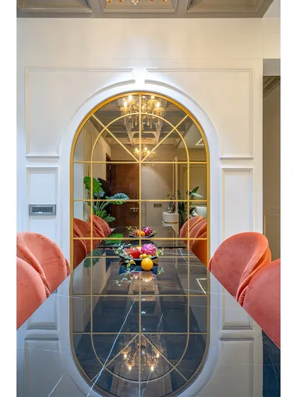 The reflection in the arched mirror doubles the impact of the crystal chandelier, creating an illusion of a larger, more opulent space. This is a technique we often use to enhance dining rooms.