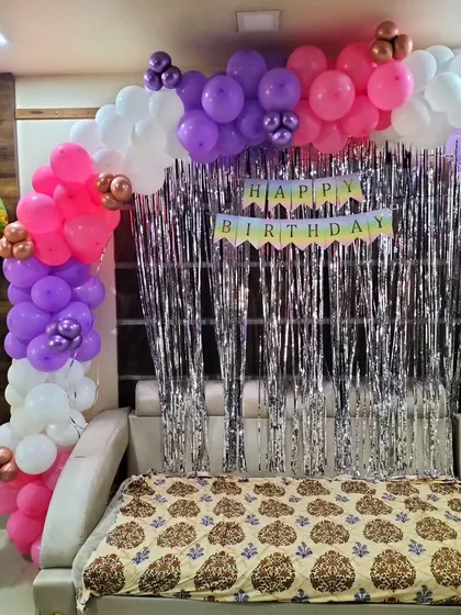 A simple backdrop for a home party. We created this balloon arch over a sofa and placed it against a silver shimmer curtain to create a festive photo corner with minimal space.