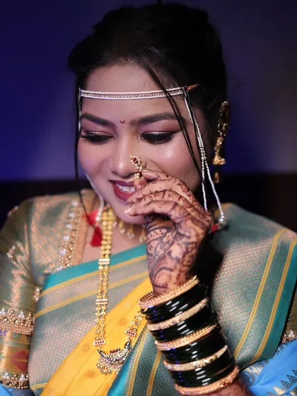 Another shot of the bride adjusting her nath, showing off her mehndi and green bangles.