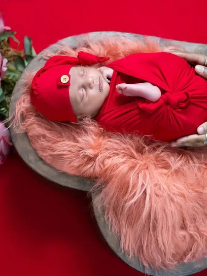 A perfectly wrapped newborn nestled in a heart-shaped bowl. This photo highlights our attention to detail in newborn photography, using soft textures, rich colors, and safe posing techniques to create adorable and artistic baby portraits.