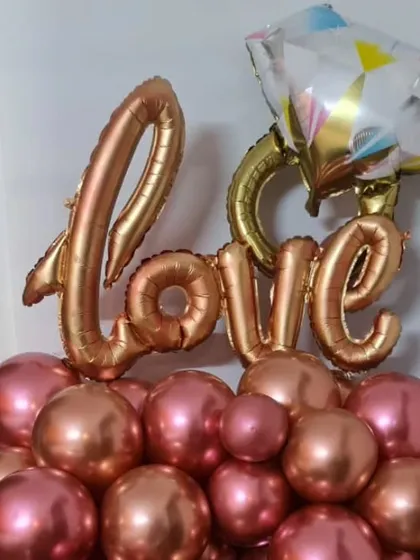 A beautiful tabletop balloon arrangement with 'Love' foil balloons and a diamond ring accent, perfect for an engagement or anniversary.