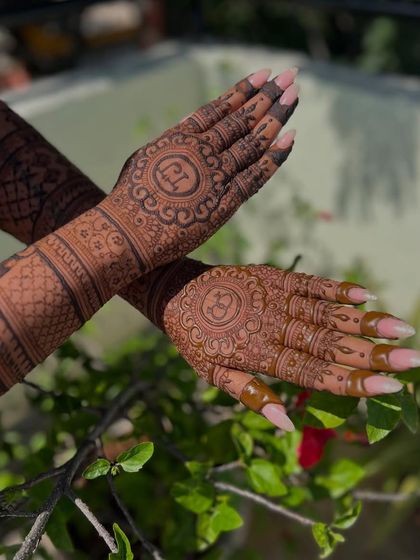 The back of the hands for this engagement set, featuring circular frames with the couple's initials. The long, elegant nails complement the design beautifully.