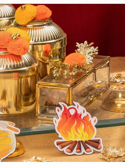 A close-up of the golden Lohri hamper, showing the detail on the jars and the festive bonfire cutout.