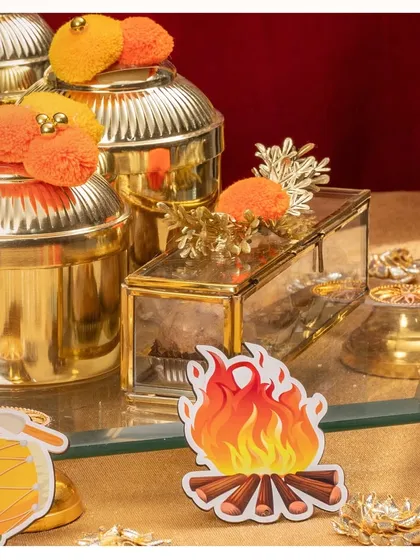 A close-up of the golden Lohri hamper, showing the detail on the jars and the festive bonfire cutout.