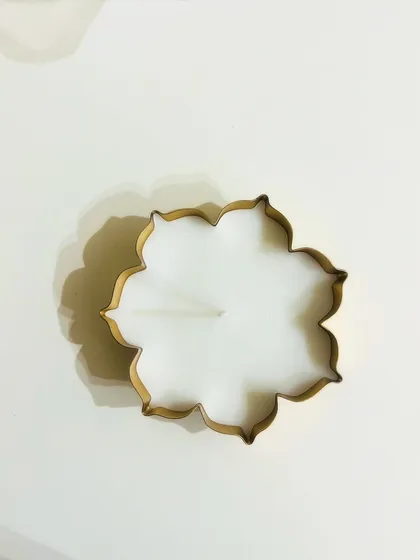 A top-down view of our new floral-shaped urli candle for the festive season. Its clean lines and golden finish make it a modern yet traditional decor piece.