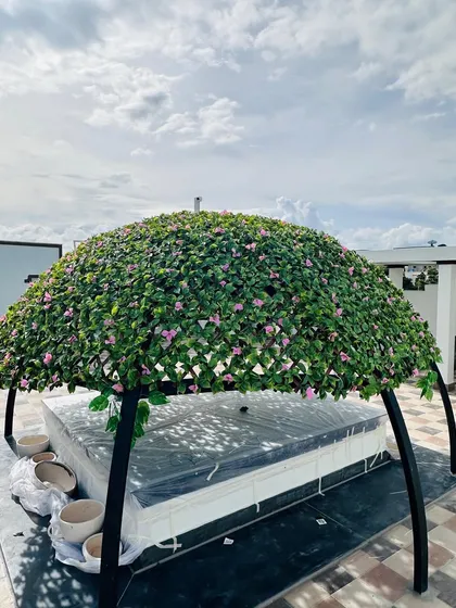 This is a custom-built rooftop gazebo I designed, covered entirely in artificial flowering vines. It provides a beautiful, shaded seating area and demonstrates how we can create unique, large-scale green structures for any outdoor space.