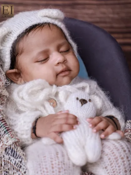 A sweet moment with the baby holding a tiny teddy bear, part of our vintage-themed photoshoot. These small details add a touch of innocence and charm.