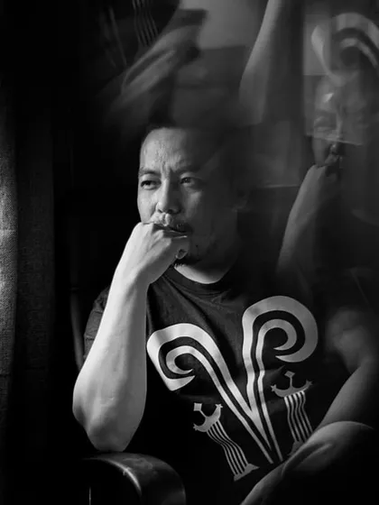 A black and white version of the portrait of Mo Naga, using a slow shutter speed to create a ghostly motion effect. This artistic choice adds a layer of depth and mystique to the artist's portrait.