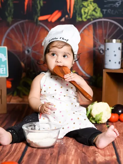 Our little chef is tasting her ingredients. I use safe, baby-friendly props to make themed shoots like this kitchen setup interactive and fun for your child.