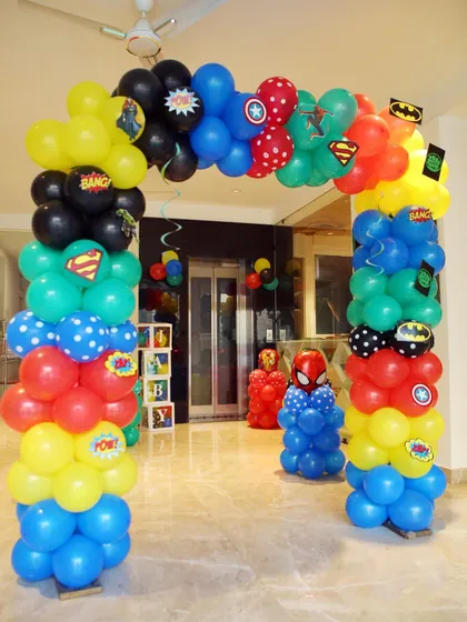 A colorful superhero balloon arch inside the venue, leading to the party area.