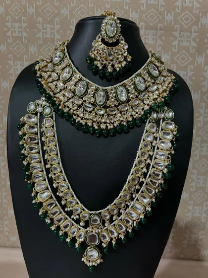 This layered green Kundan bridal set is perfect for the bride who wants a complete and coordinated look. The set includes a choker, a long necklace, and matching earrings and maang tikka.