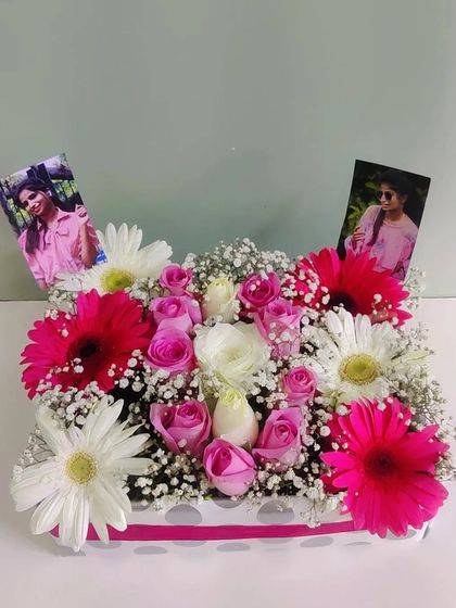 A box full of memories and beautiful blooms. This arrangement features bright pink gerberas, soft pink roses, and personal photos tucked into the flowers, making it a deeply personal and heartfelt gift.