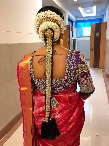 Another example of a stunning South Indian bridal braid. This one features a large gajra bun and a long, decorated braid with gold accessories, a truly regal hairstyle.