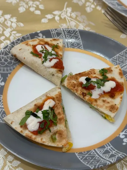 A perfectly plated serving of our vegetarian quesadillas, cut into triangles and topped with fresh salsa and cream. A delicious taste of our Mexican cuisine.