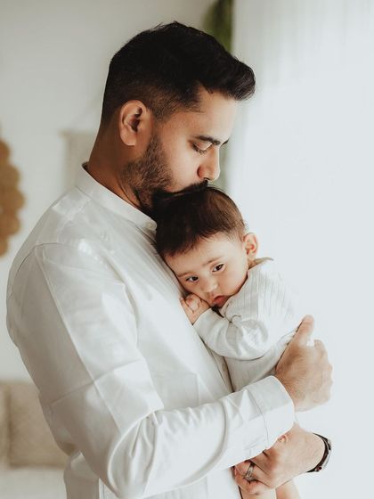 A father's gentle kiss on his baby's head. This warm, candid shot captures a quiet moment of paternal love and tenderness.