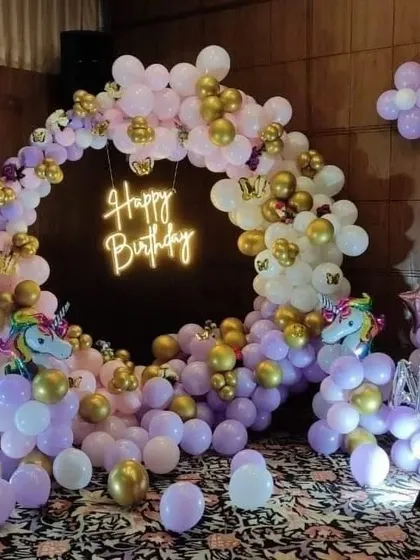 An elegant unicorn-themed first birthday. This beautiful arrangement uses pastel purple and white balloons with gold accents, a neon sign, and a light-up number '1'.