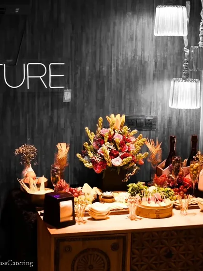 The full view of our catering setup for a couture brand's event. The stylish grazing table is set against a modern backdrop with a neon sign, showing how we integrate our design with the client's brand identity.