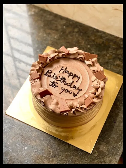 A simple and elegant chocolate truffle birthday cake, topped with chocolate chunks and piped swirls.