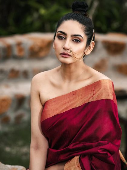 A fusion-style ethnic shoot, combining a traditional saree drape with a modern, minimalist aesthetic. The natural, stony background adds a raw and earthy feel to this confident portrait.