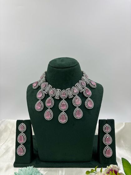 A modern necklace set with large, teardrop-shaped stones in a cascading design. This piece is available in several colors, including pink, green, and red, offering a bold and stylish look.