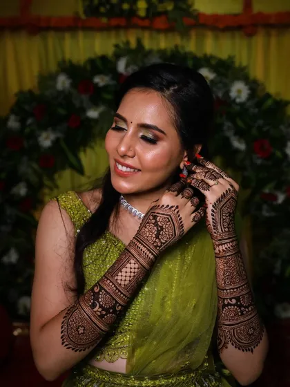 A candid moment of the bride adjusting her earring, giving a beautiful view of the intricate henna work.