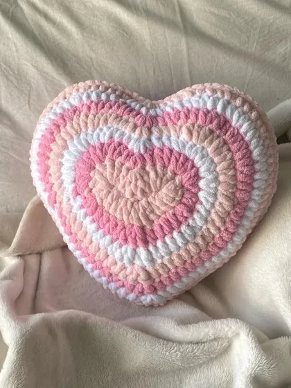 Our handmade crochet heart pillow, styled on a soft blanket. It's a perfect gift for Valentine's Day or any day you want to share some love.