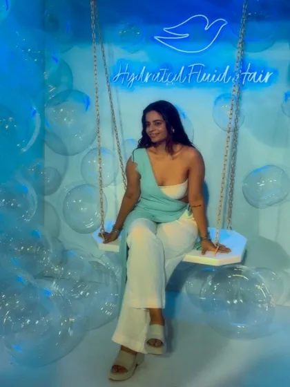 Posing on a swing at the Dove event. The draped top and wide-leg pants create a beautiful, elongated silhouette that is both comfortable and elegant.