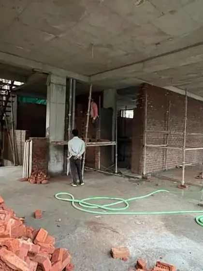 An interior view during the construction phase. This image captures the raw space before finishes are applied, with piles of red bricks ready for the walls that will soon define the home's interior layout.