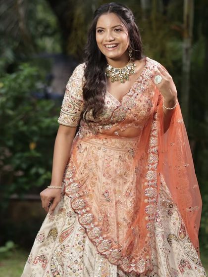 A happy client in a beautiful peach and off-white embroidered lehenga. The soft colors and intricate work make it a wonderful choice for a daytime engagement.