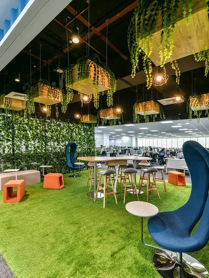 We love bringing the outdoors in. This biophilic breakout zone features an artificial grass floor, unique high-backed chairs, and planters suspended from the ceiling, creating a refreshing park-like atmosphere right inside the office.