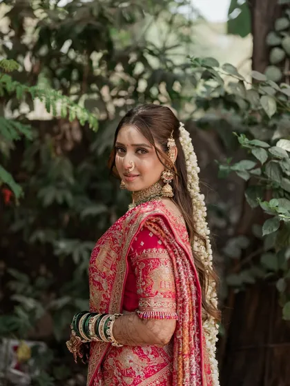 A symphony of love and tradition. This bride's look features a soft, romantic makeup style with a beautiful long hairstyle adorned with fresh flowers, perfect for her pink bandhani saree.