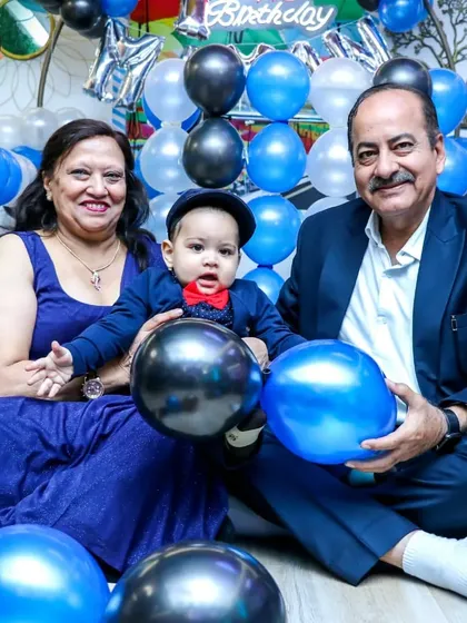 A first birthday is a milestone for the whole family. Here, a happy family celebrates with their one-year-old, surrounded by custom blue and silver balloon decorations.