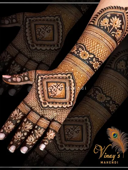 A bold back-of-hand design with the sacred 'Shri' symbol enclosed in a square frame. The design is balanced with floral bands and lotus motifs on the fingers.