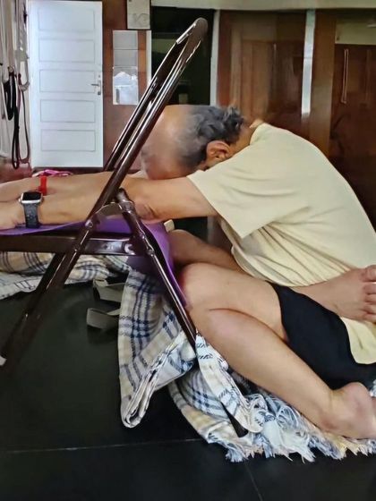 A seated forward fold over a chair.