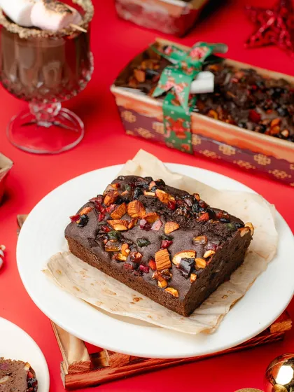 A slice of rich plum cake from our Christmas series. The festive red background and props make it the perfect holiday dessert shot.