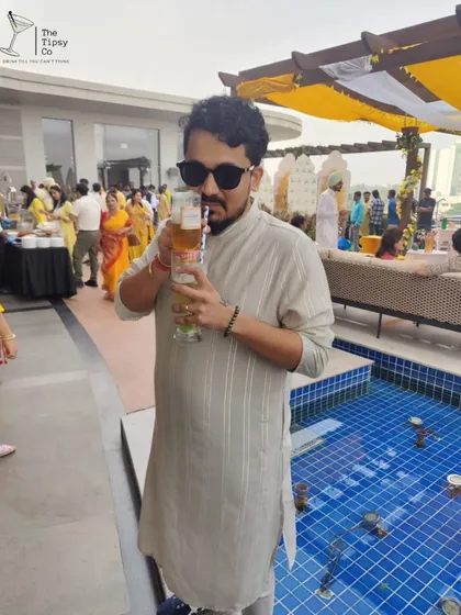 A guest enjoying a tall, refreshing drink by the pool at a daytime event. We cater to all parts of a celebration, from the relaxed afternoon to the high-energy evening.