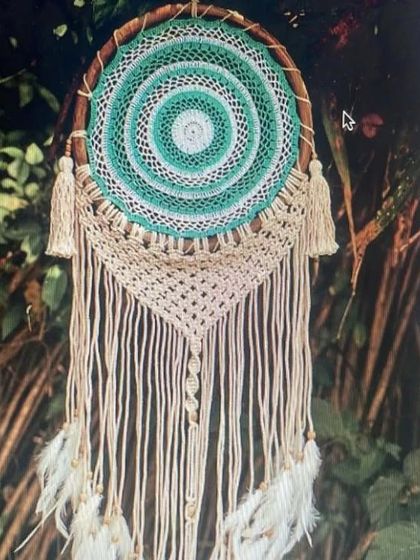 A beautiful handmade dream catcher with a mix of macrame and crochet work. The green and white colors and feather details make it a peaceful and positive addition to your home.