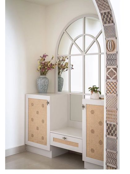 The foyer's shoe storage and seating unit, featuring a mirror that echoes the arch's shape. The design uses cane shutters and a clean white finish to create a bright and functional entryway.