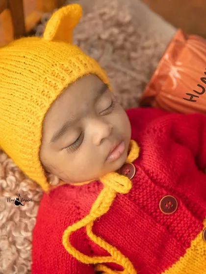 A close-up on the knitted Pooh costume, showing the beautiful details and the baby's peaceful face. Every part of the session is crafted with care.