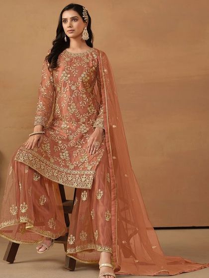 A beautiful dark salmon net suit with sharara pants. The delicate sequence work gives it a soft shimmer, perfect for a daytime wedding or festive gathering.