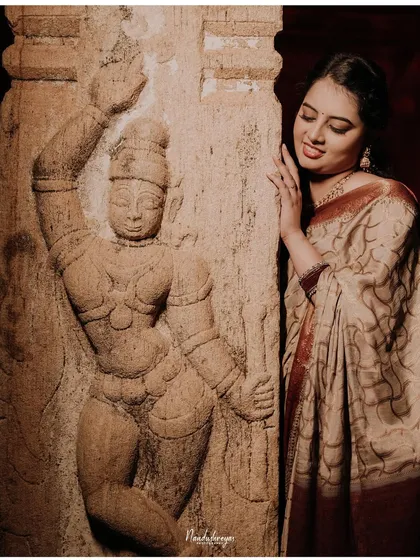 A solo portrait of the bride-to-be admiring the intricate carvings on a temple pillar, connecting with the heritage of the location.