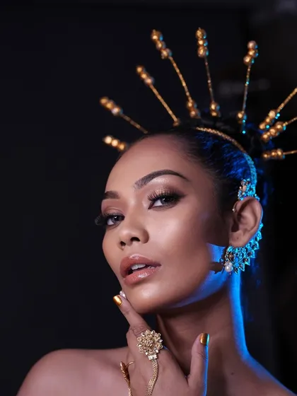 The same look under blue lighting, showing how the makeup and gold accessories interact with different lighting setups.