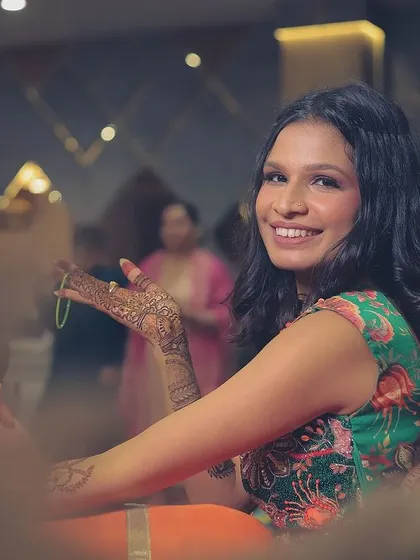 A candid shot of the bride during her mehendi ceremony, looking over her shoulder with a bright smile.