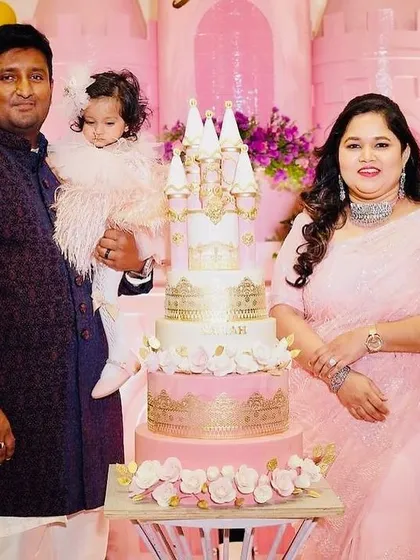 A happy family portrait at Sarah's princess party, posing in front of the pink castle backdrop with the stunning castle cake.